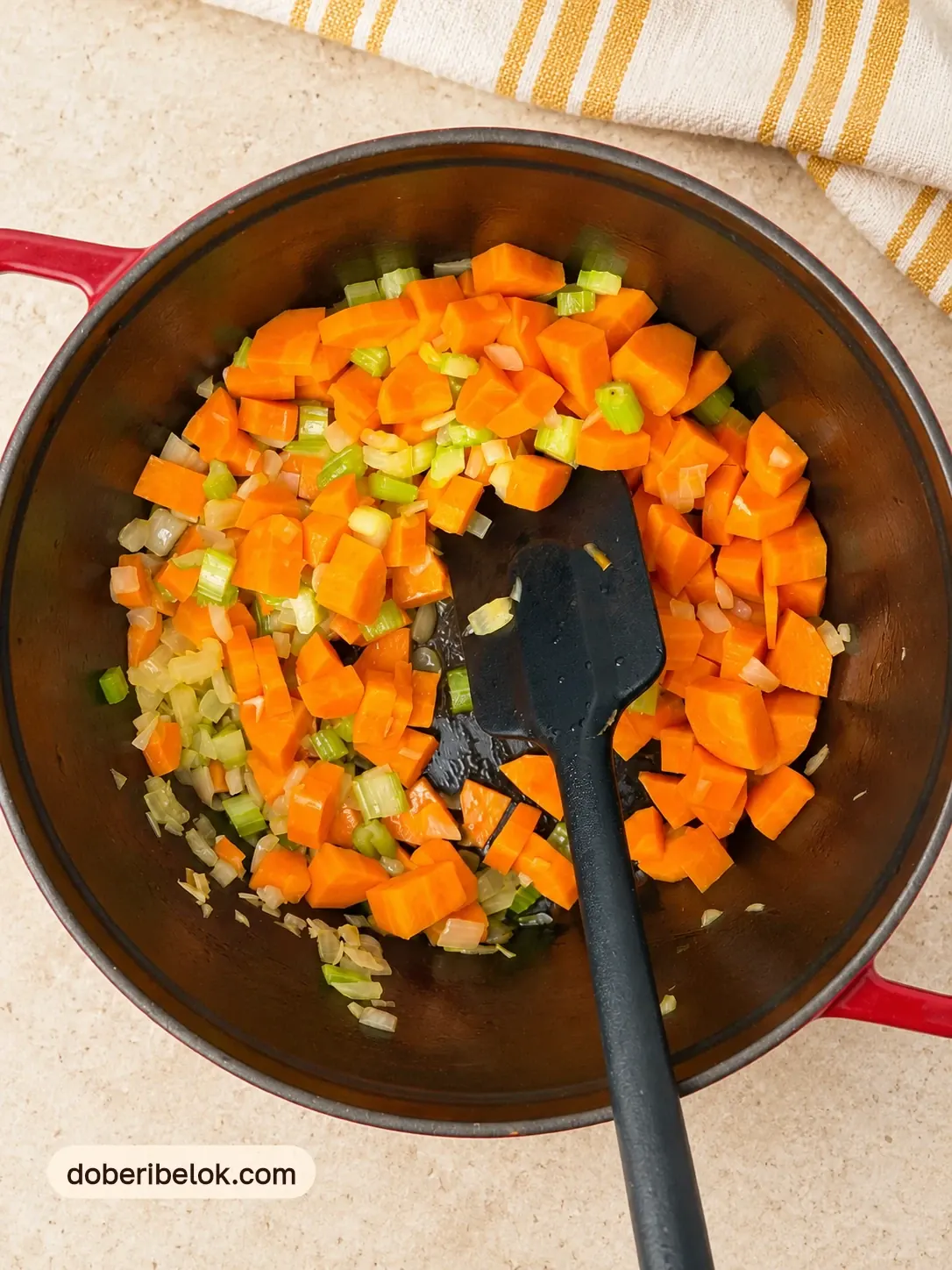 Кубики моркови, лук и сельдерей обжариваются в кастрюле с чёрной лопаткой