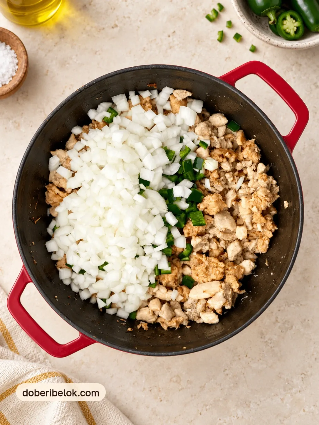 Обжаренная курица с фаршем в кастрюле, сверху нарезанный лук и халапеньо