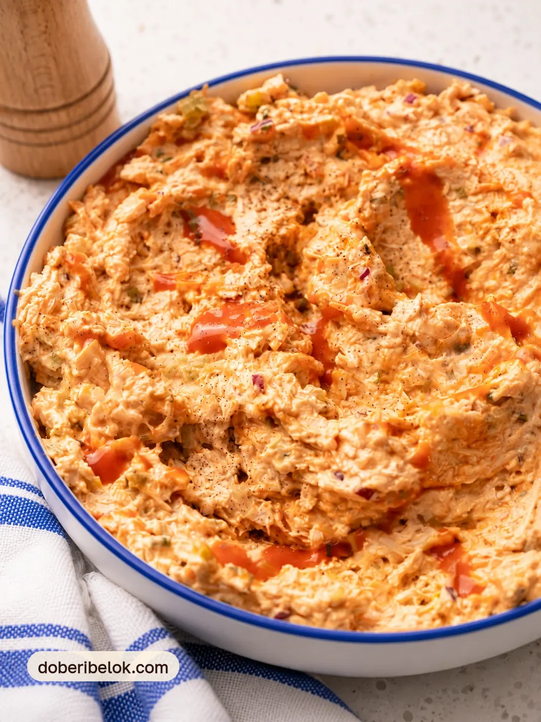 Куриный салат «Баффало» крупным планом с полосками острого соуса и молотым перцем