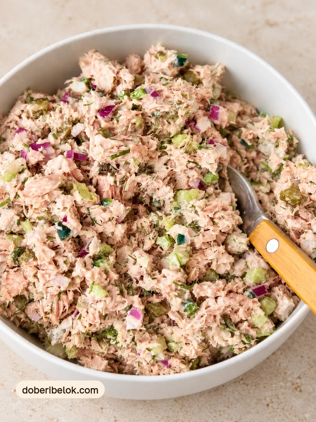 Перемешанный салат с тунцом и солёными огурцами крупным планом с ложкой