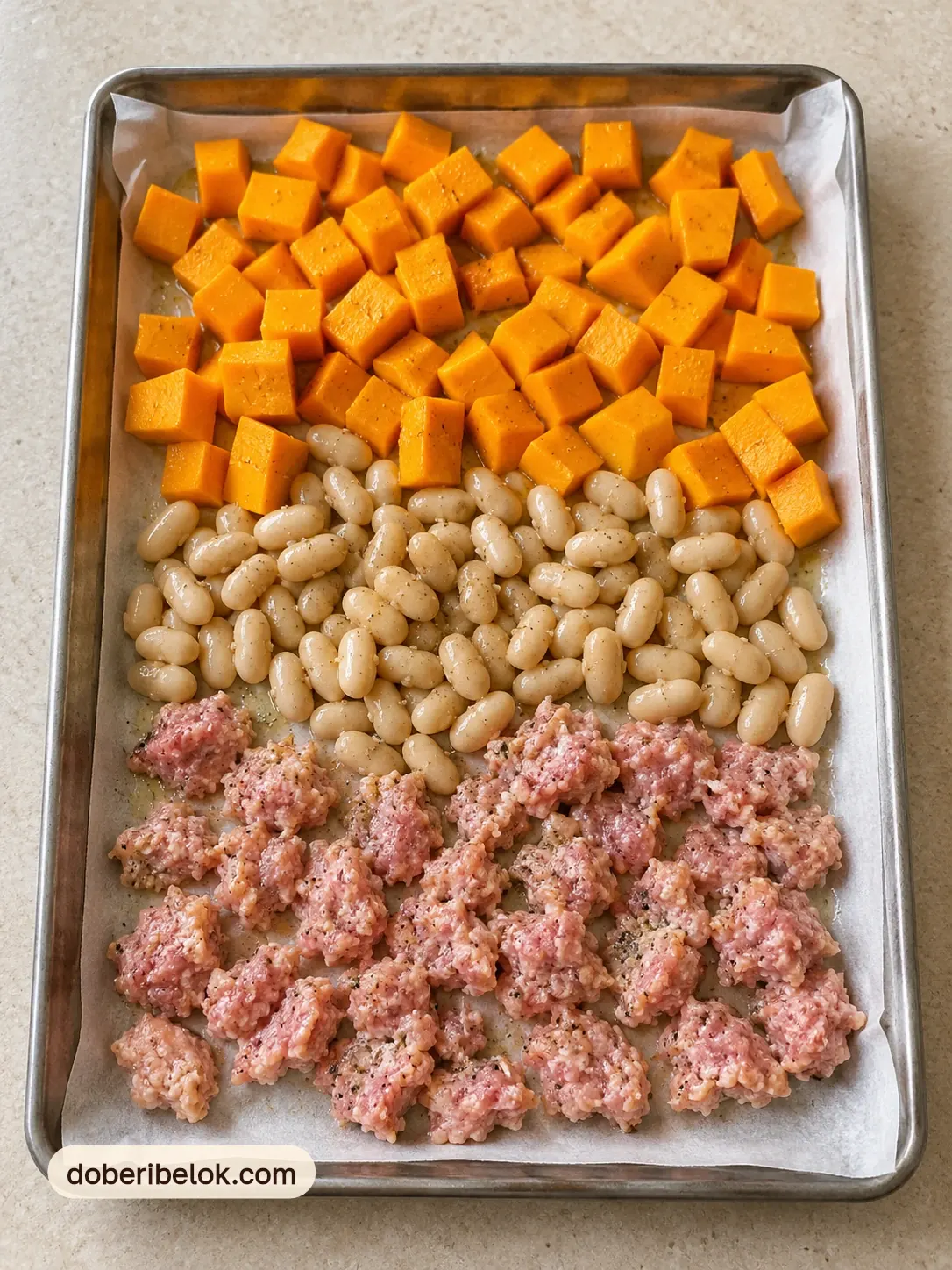 Сырые кубики тыквы, белая фасоль и куриный фарш на противне с пергаментом